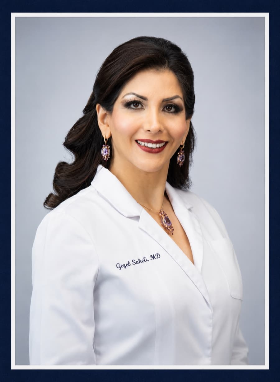 Gezel Saheli, MD, smiling in a white physician's coat.